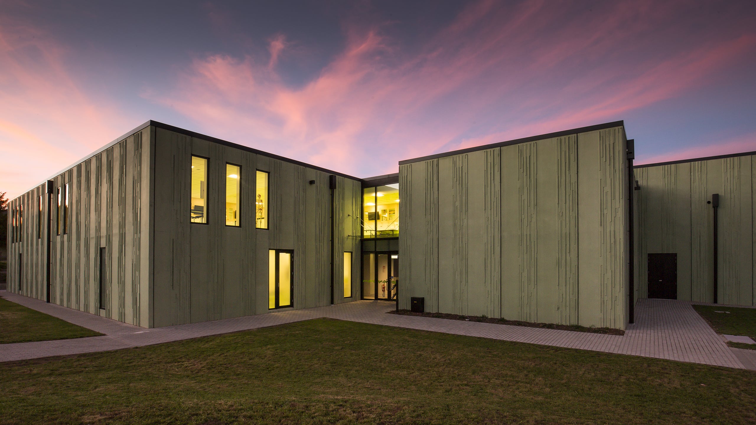 the sun sets behind the coloured concrete walls of Waiariki Nursing Building