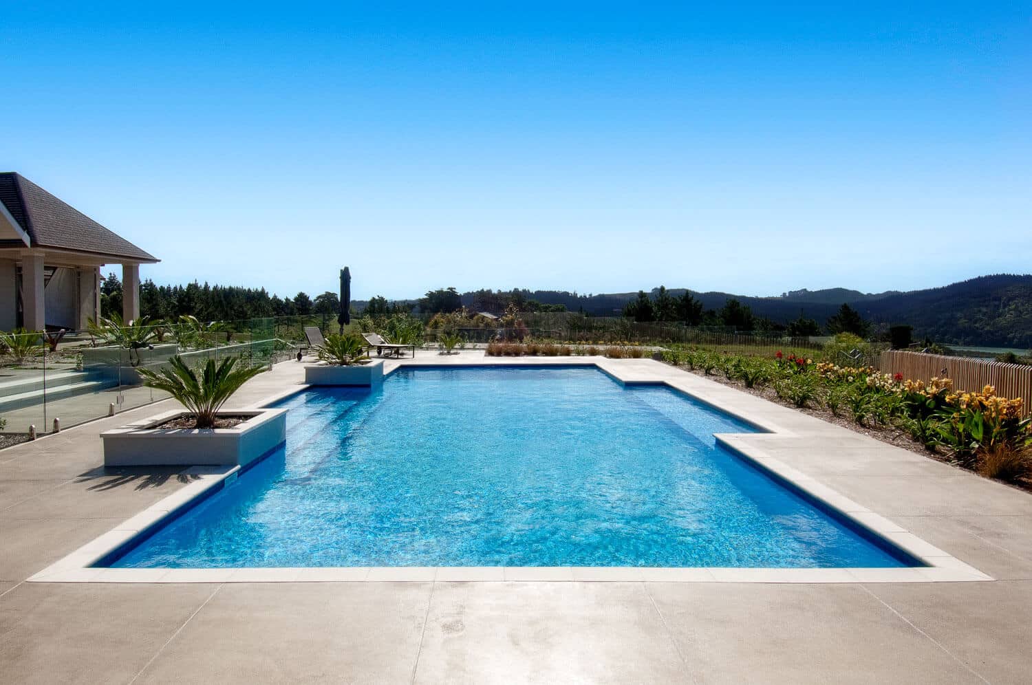 Coloured concrete pool surround rectangular pool.