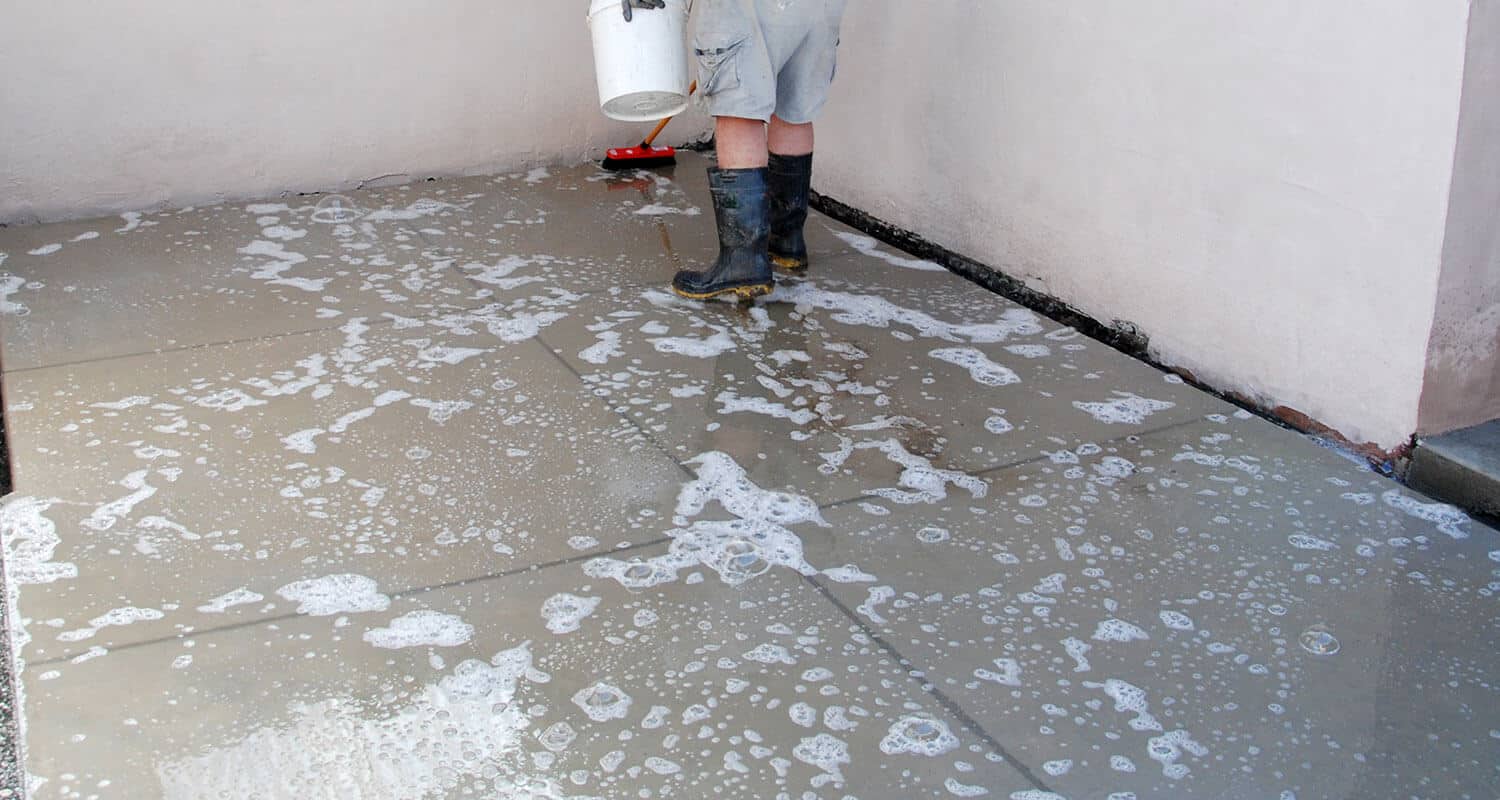 Man cleaning concrete prior to sealing step 4